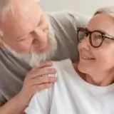 Man and woman in glasses smiling while looking at each other