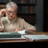 Desk with books and papers in front of woman in glasses