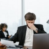 Main in business suit rubbing eyes